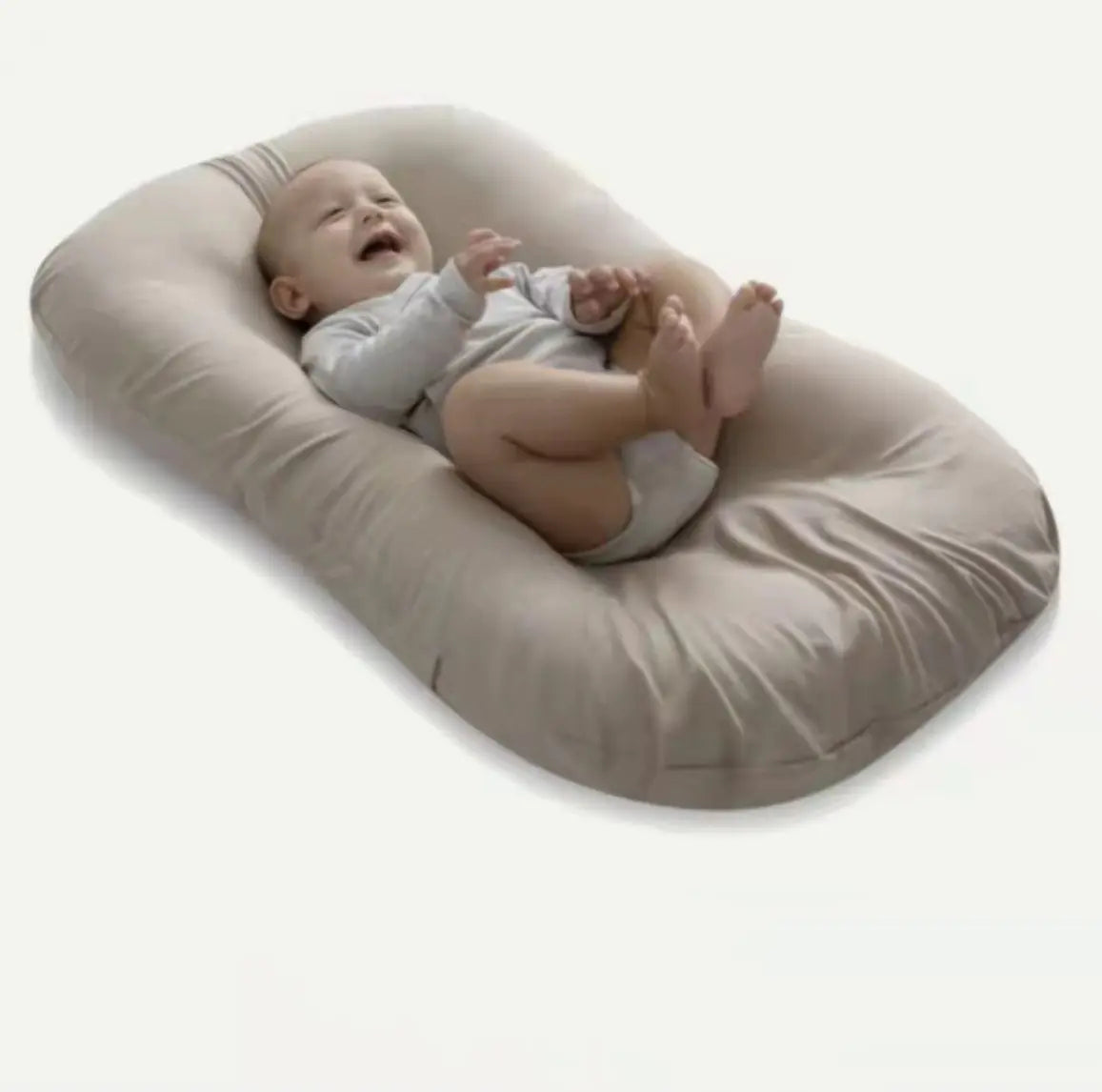 Newborn baby sleeping securely in a womb-like bionic nest on a bed.